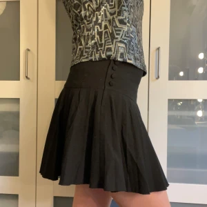 Svart kjol - Svart plisserad miniskirt från HM i storlek 42, passar också en 40! Dragkedja vid knapparna på kjolen! I mycket fint skick. 