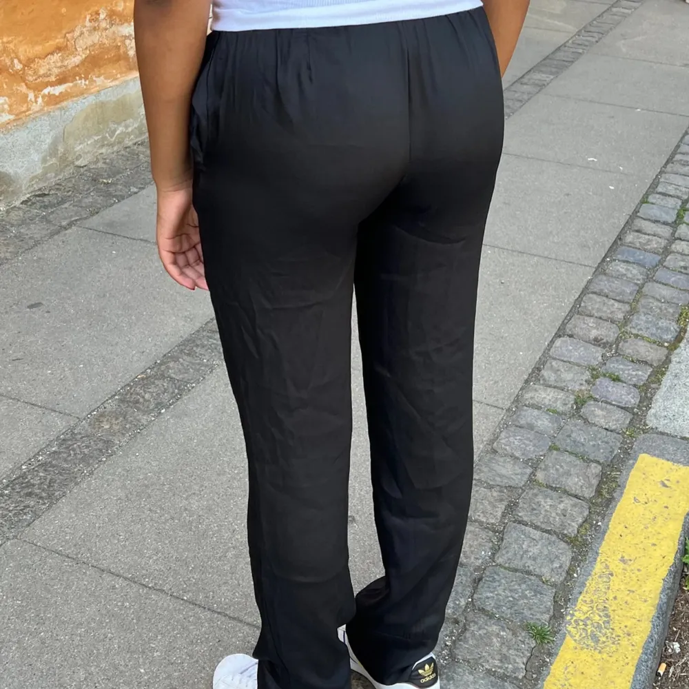 Säljer ett par svarta byxor i satin med loose fit. De är lågmidjade och har en elastisk midja för extra komfort. Perfekta för både vardag och festliga tillfällen. Passar bra till en enkel topp eller en mer dressad look. Säljer då de är för små.. Jeans & Byxor.