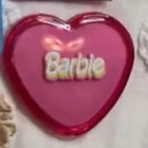 Hjärtformad sminkpalett från Barbie - Söt hjärtformad sminkpalett från Barbie i en härlig rosa färg. Perfekt för att lägga till en touch av färg och glans till din look. Den är kompakt och lätt att ta med sig i väskan för snabba touch-ups under dagen. En måste-ha för alla Barbie-fans!