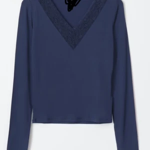 Marinblå  långärmad topp med spetsdetalj - Säljer en snygg mörkblå långärmad topp med en v-ringad spetsdetalj. Perfekt för både vardag och fest! Den är i mycket bra skick och passar perfekt till jeans eller kjol. Superbekväm och stilren!