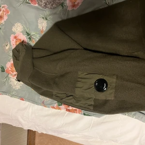 Olivgrön jacka från C.P. Company - Säljer en olivgrön jacka från C.P. Company i mycket bra skick. Jackan har en dragkedja framtill och praktiska fickor med knappar. Perfekt för höst och vår med sin stilrena design och bekväma passform. Passar både till vardags och lite finare tillfällen.