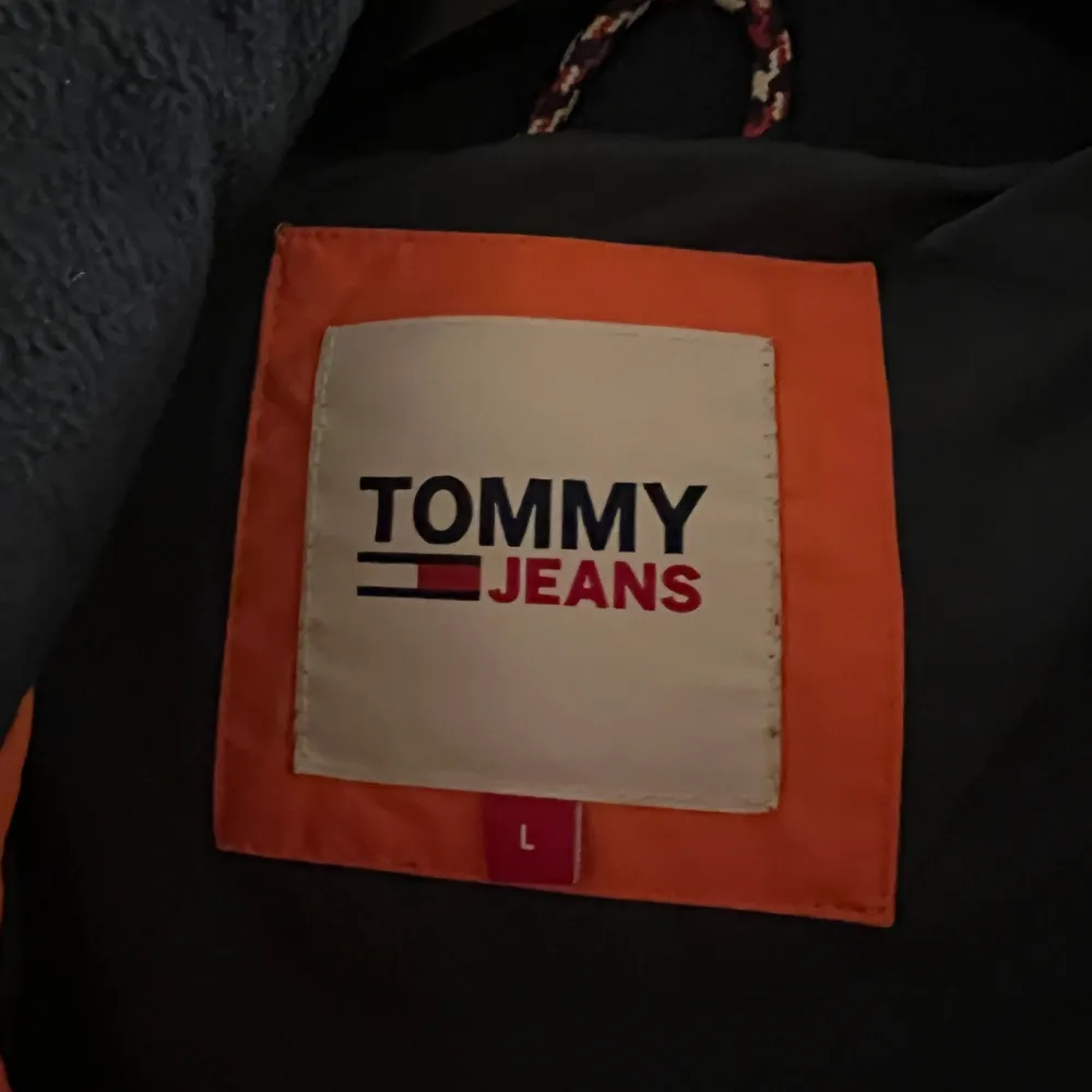 Säljer en snygg orange pufferjacka från Tommy Hilfiger. Den har en dragkedja framtill och en mysig huva med snörning. Perfekt för kalla dagar och ger en cool look med sin starka färg. Jackan är i mycket bra skick!. Takit.