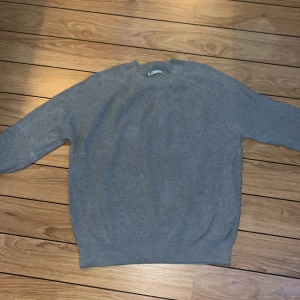 Grå stickad tröja från Zara - Säljer en stilren grå stickad tröja från Zara i storlek L. Perfekt för kyliga dagar med sin mjuka och bekväma passform. Tröjan har långa ärmar och en klassisk rund halsringning. Passar både till vardags och lite finare tillfällen. 🧶