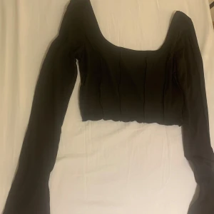 Svart topp  - Svart topp som är något croppad och har utsvängda armar. 