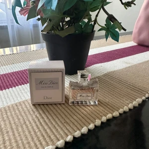 Miss Dior Eau de Parfum - Säljer en elegant och lyxig Miss Dior Eau de Parfum. Flaskan är stilren med en söt rosett och innehåller 5 ml av den ikoniska doften. Perfekt för speciella tillfällen eller som en fin present. Kommer i originalförpackning.
