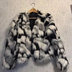 Svartvit pälsjacka - Säljer en fluffig och trendig svartvit pälsjacka med ett iögonfallande mönster. Jackan har långa ärmar och en oversized passform, perfekt för att hålla sig varm och stilren under kyliga dagar.