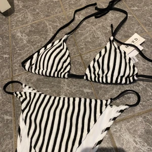 OANVÄND randig bikini från NA-KD - Snygg svartvit randig bikini från NA-KD med knytband. Triangelformad topp och matchande underdel. Helt oanvänt med alla lappar kvar