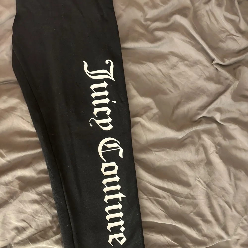 Snygga svarta mjukisbyxor från Juicy Couture med stort tryck längs benet. Perfekta för en avslappnad stil med elastisk midja och dragsko för bästa passform, fickor på sidorna. Lite använda storlek small . Farkut & Housut.