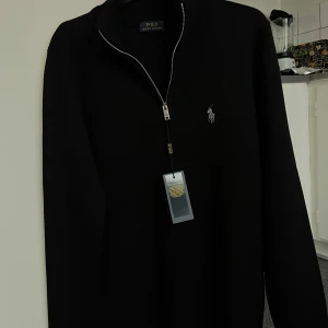 Polo Ralph Lauren - Snygg svart tröja från Polo Ralph Lauren med dragkedja och Perfekt för en stilren look. L&M finns. 