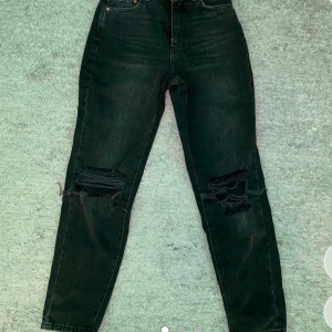 Svarta jeans med slitningar - Snygga svarta jeans från Perfect Jeans med coola slitningar på knäna. De har en hög midja och en straight passform som ger en avslappnad look. Perfekta för en trendig stil.