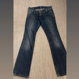 Blå jeans från Lee - Säljer ett par klassiska blå jeans från Lee. De har en bootcut-stil och är tillverkade i jeansmaterial. Perfekta för en avslappnad look. Jätte lågmidjade och snygga på älskar dom!