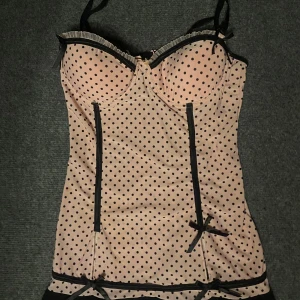 Rosa prickig korsett topp - den är storlek xs-s !Säljer en söt rosa korsett från Rampage med svarta prickar och detaljer. Den har justerbara axelband och en liten rosett framtill. Perfekt för en speciell kväll!