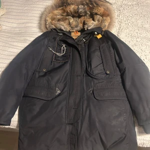 Parajumpers - Säljer en svart parkajacka från Parajumpers med pälsfodrad huva. Jackan har flera praktiska fickor och en dragkedja framtill. Perfekt för kalla vinterdagar. I väldigt fint sick pedant sköt 