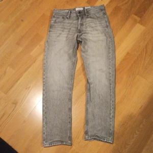 Grå jeans från Jack & Jones - Snygga grå jeans från Jack & Jones i modellen Loose/Chris. De har en loose passform och klassisk femficksdesign med knappgylf. Perfekta för en avslappnad stil. Nypris 600kr, väl använda men fortfarande väldigt dint skick. Pris kan diskuteras😁. Storlek 27,30