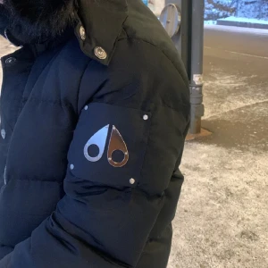 Moose knuckles (svart päls)❗️ -                                                                          Sälljer svart dunjacka från Moose Knuckles med pälskrage och flera praktiska fickor. Jackan har en design på sidan och kommer med dragkedja och knappar samt en logotyp på ärmen. ingen restur.  Perfekt för vinterdagar. (SUPER VARM)                                                                          -PRIS KAN DISKUTERAS VID SABB AFFÄR❗️                 