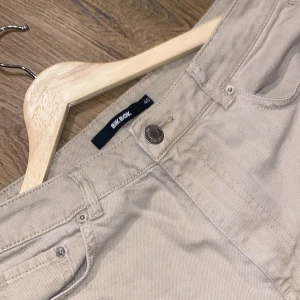 Beige byxor från Bik Bok - Snygga beige byxor från Bik Bok med klassisk design. De har en rak passform och är perfekta för en stilren look. Byxorna har fem fickor och knappstängning framtill. Har någon enstaka fläck men som ej syns därav priset 