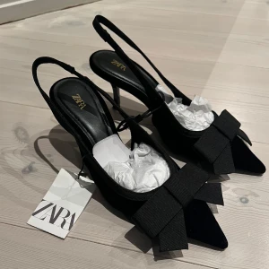 Svarta klackskor med rosett från Zara - Svarta klackskor i sammets-look från Zara stl 35! Skorna har spetsig tå, öppen häl samt rosett🎀 Perfekta för en stilren look till antingen klänning, kjol eller kostymbyxor🖤Klackhöjden runt 6 cm men sulhöjden 8 cm enligt Zaras hemsida. Endast provade med lappen kvar, skickas med dustbag!😇
