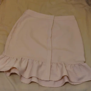 Tight rosa kjol - Tight ljusrosa kjol med volanger i nederkanten, bra material 