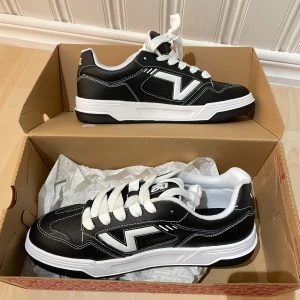 Svarta och vita sneakers från Vans helt nya oanvända  - Säljer ett par snygga svarta och vita Vans sneakers med klassisk snörning. Skorna har en stilren design med vita detaljer och en bekväm passform. Perfekta för en avslappnad stil. Helt nya oanvända skor!!