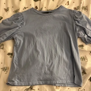 Ljusblåtopp - Fin ljusblå topp med ballong ärmar, använd men i fint skick. Normal i storleken.