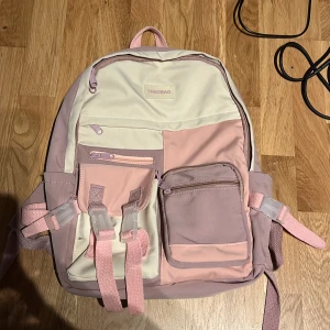 Kawaii ryggsäck - Kawaii ryggsäck i rosa och lila med flera praktiska fickor och justerbara remmar Perfekt för vardagsbruk och utflykter. Har några fläckar och därför är priset så billigt. Skit söt och perfekt för tex skolan🌸🤍
