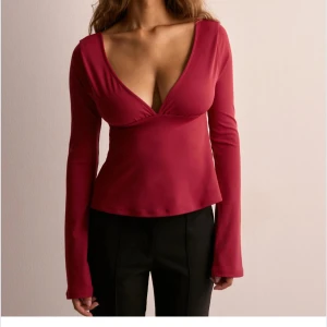 Röd långärmad topp med knyt - Snygg röd topp med djup v-ringning och långa ärmar. Toppen har en öppen rygg med en dekorativ rosett. Perfekt för en kväll ute eller en speciell tillställning. Helt ny med lappar kvar🩷kostar 299kr på hemsidan 