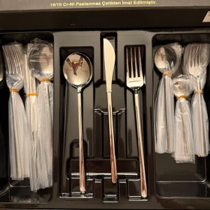 36 delar helt ny - Elegant bestickset i rostfritt stål med spegelblank finish. Setet innehåller gafflar, knivar och skedar, alla individuellt förpackade i plast. Perfekt för både vardag och festliga tillfällen.
