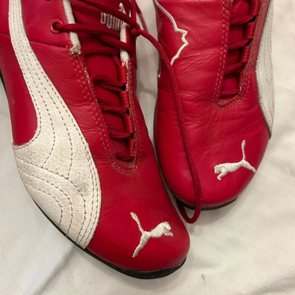 Snygga vintage röda Puma sneakers med vit detaljering och Ferrari-logga på sidan. Skorna har snörning och är tillverkade i syntetmaterial.. Kengät.