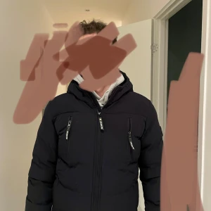 Mörkblå pufferjacka från Cars Jeans - Snygg svart pufferjacka från Cars Jeans med dragkedjor och hög krage. Perfekt för kyliga dagar med sin vadderade design. Jackan har flera praktiska fickor med dragkedja. Storlek 164 - så för liten för brorsan som har storlek M idag. 