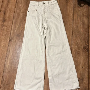 Vita wide jeans från Zara - Säljer ett par vita wide jeans från Zara. Byxorna har hög midja och fransiga kanter vid bensluten för en trendig look. Perfekta för en stilren outfit.