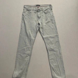 Ljusa jeans från Tommy Hilfiger - Snygga ljusblå jeans från Tommy Hilfiger med tapered fit och stretch för extra komfort. De har klassisk femficksdesign och en diskret logga på bakfickan. Perfekta för en stilren look. Strl 31/34