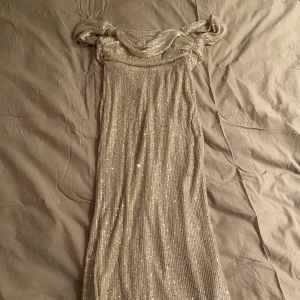 Balklänning glittrig  - Säljer nu min super vackra balklänning, den är beige med silvriga paljetter den sitter off shoulder och ör väldigt lång. Den är använd en gång på min bal så är i super bra skick!❤️jag köpte den helt ny  för 1300❤️ skriv till mig för bilder me den på! 