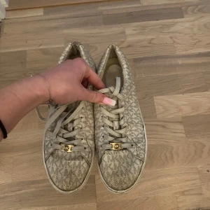 Michael kors skor  - Säljer beiga Michael kors skor i storlek 40.5 i använt skick men är fortfarande användbara. Finns ett hål framme vid skon (syns på 3dje bilden) kommer såklart att rengöras innan de skickas iväg. Köptes för 1600kr säljer för 250kr. Låda medföljer. 