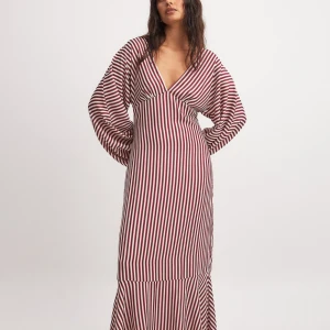 Randig långklänning med vida ärmar - Snygg långklänning med rödvita ränder och vida ärmar. Klänningen har en djup v-ringning och en elegant passform som ger en stilren look. Perfekt för en chic och modern stil.