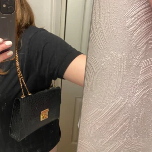 Svart handväska  - Svart handväska med guld detaljer. Perfekt vardagsväska! Den har ett fack & kan även användas som cross over väska 🤍Kedjan har rostat lite, därav skicket! 
