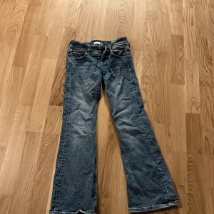 Blå jeans från Gina Tricot i storlek 140 - Säljer ett par klassiska blå jeans från Gina Tricot. De har en bootcut-stil och är tillverkade i jeansmaterial. Perfekta för en avslappnad look.