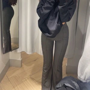 Grå bootcut/flare kostymbyxor - SÄLJER ÄVEN I SVART Snygga grå bootcut/flare kostymbyxor med hög midja. Perfekta för en stilren look och passar bra till både vardag och fest. Byxorna har en klassisk design som ger en smickrande siluett.