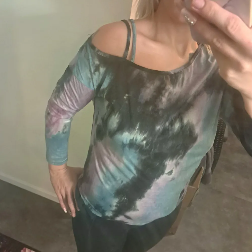 Säljer en cool offshoulder topp med batikmönster i svart, blått och lila. Toppen har långa ärmar och en avslappnad passform, perfekt för en avslappnad stil.. Yläosat.