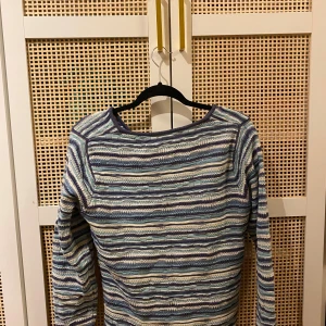 En blå randig stickad tröja  - En blå randig stickad tröja i storlek M. Tröjan har ej använts på 8 månader och är ifrån amica