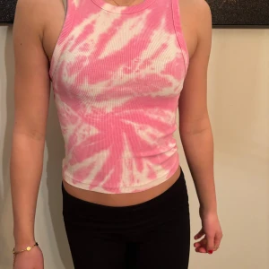 Rosa och vit ribbad linnetopp - Snygg rosa och vit ribbad linnetopp med tie-dye mönster. Perfekt för sommardagar med sin ärmlösa design och croppade passform. Ett måste för garderoben! Är en s men sitter som en xxs. 