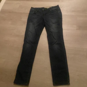Mörkblå jeans från Diesel - Säljer ett par mörkblå jeans från Diesel. Klassisk design med knappgylf och raka ben. Perfekta för en stilren look.