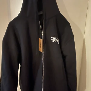 Basic stussy zip hoodie  - Tjena säljer en helt oanvänt zip hoodie ifrån stussy storlek m och taggen hänger kvar. 1500 kr 