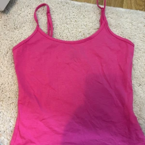 Rosa linne - Säljer ett enkelt och snyggt rosa linne med tunna axelband. Perfekt för sommardagar eller som ett basplagg i garderoben. Linnet är i ett mjukt och bekvämt material.