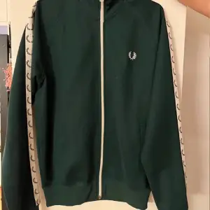 Säljer en mörkgrön fred Perry tracktop i storlek M, väldigt bra skick knappt använd.