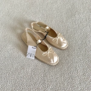 ZARA ballerina / espandrillos skor med rosett - Så himla fina krämvita ballerinaskor / espandrillos i satin-liknande material med rosett från ZARA. Väldigt bekväma att gå i tack vare stretchig häl. Nya med prislapp.