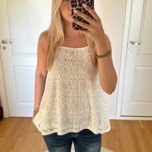 Vit mönstrad ärmlös topp - Säljer en superfin vit ärmlös topp med ett snyggt geometriskt mönster. Perfekt för sommardagar eller en avslappnad fest. Toppen är luftig och bekväm, vilket gör den idealisk för varma dagar. Passar mig med storlek S!💘