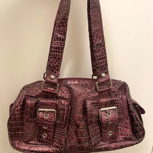 Handväska - Lila supersnygg väska köpt secondhand, den är skavd på flera ställen. Botten är ca 32 cm lång. 