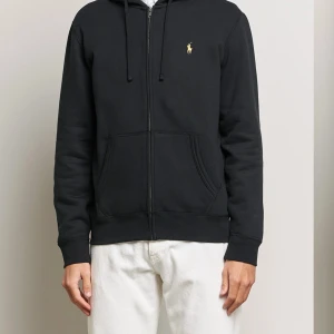 Ralph Lauren zip hoodie svart i strl L  - Säljer nu min Ralph lauren zip hoodie då jag ej använder den. Den är i extremt bra skick då jag bara använt den ett par gånger. Nypris på denna ligger på 2200kr och är helt slutsåld på alla hemsidor. Tveka inte på att höra av dig vid fler frågor:)