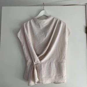 Tunn blus från BooHoo - Lätt beige, tunn blus från BooHoo. Köpt för 350. Aldrig använd. Säljer då den är för liten. Skriv om du vill ha fler bilder eller undrar något!