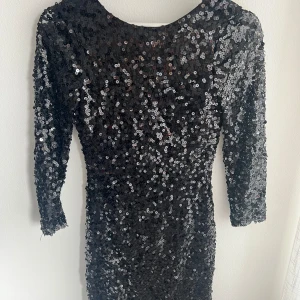 Paljettklänning med öppen rygg från Oneness - Klänningen är i storlek S/36 och har dubbeltyg längst kroppen men transparent på armarna. 